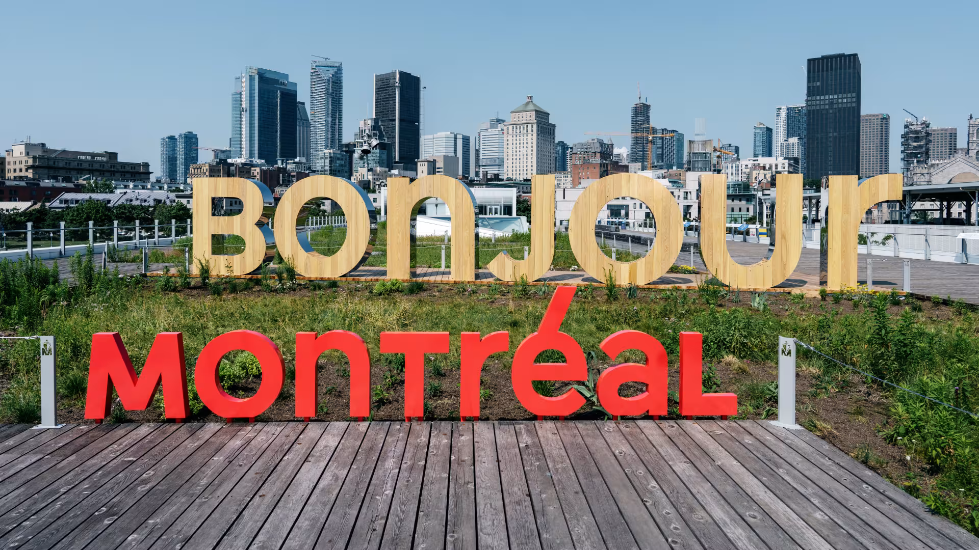 City Of Montreal day time skyline. The words Tourisme/ Montréal/Montre’al written over it. The word bonjour appears made of pine in foreground